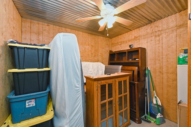 miscellaneous room featuring ceiling fan and wooden walls