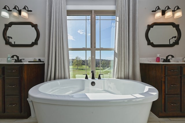 bathroom featuring a washtub, vanity, tile patterned flooring, and a healthy amount of sunlight