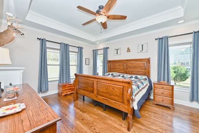 bedroom featuring a tray ceiling, ceiling fan, wood-type flooring, and ornamental molding