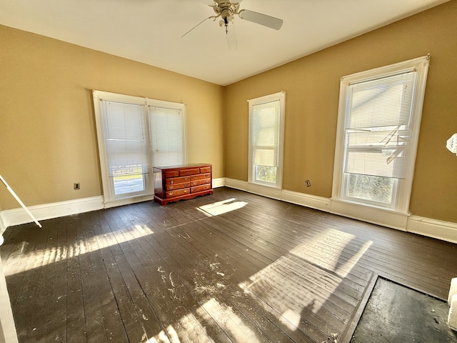 empty room with dark hardwood / wood-style floors, ceiling fan, and a healthy amount of sunlight