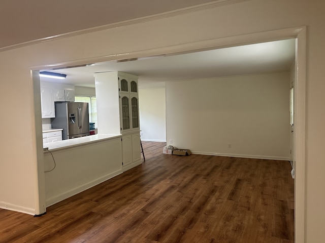 unfurnished living room with ornamental molding and dark wood-type flooring