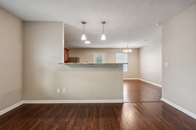 kitchen with hanging light fixtures, dark hardwood / wood-style flooring, kitchen peninsula, stainless steel fridge, and a textured ceiling