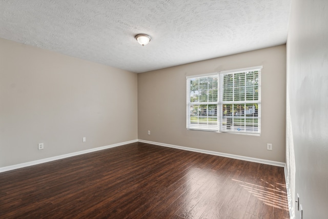 spare room featuring dark hardwood / wood-style flooring and a textured ceiling