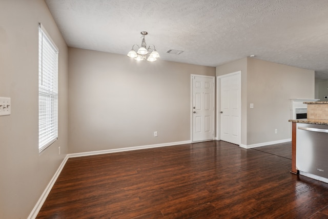 interior space featuring plenty of natural light, dark hardwood / wood-style flooring, a textured ceiling, and an inviting chandelier