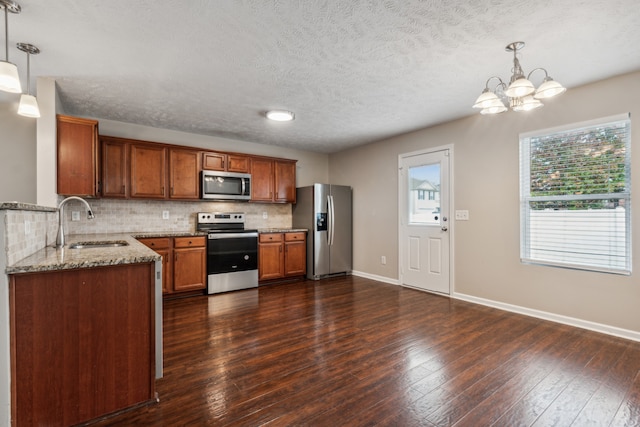 kitchen featuring light stone countertops, stainless steel appliances, sink, dark hardwood / wood-style floors, and hanging light fixtures