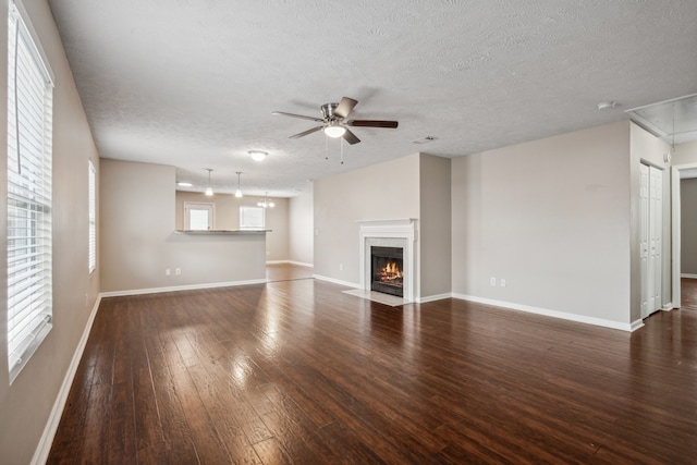 unfurnished living room featuring a textured ceiling, ceiling fan, and dark wood-type flooring