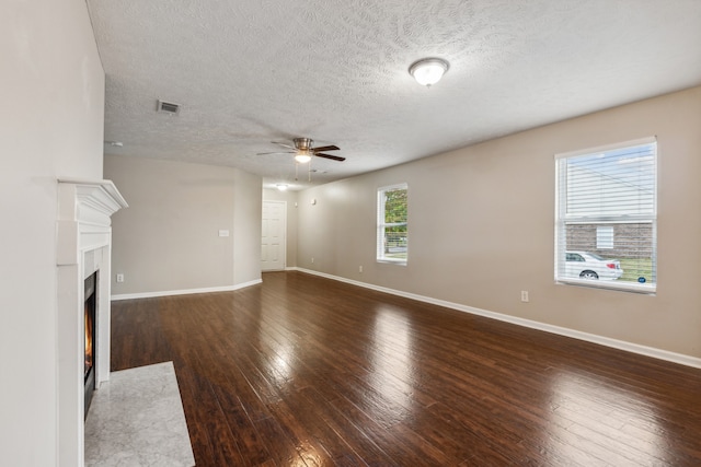 unfurnished living room featuring a textured ceiling, dark hardwood / wood-style flooring, and ceiling fan