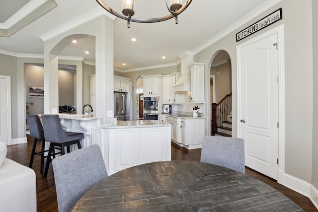 dining space featuring an inviting chandelier, sink, crown molding, and dark wood-type flooring