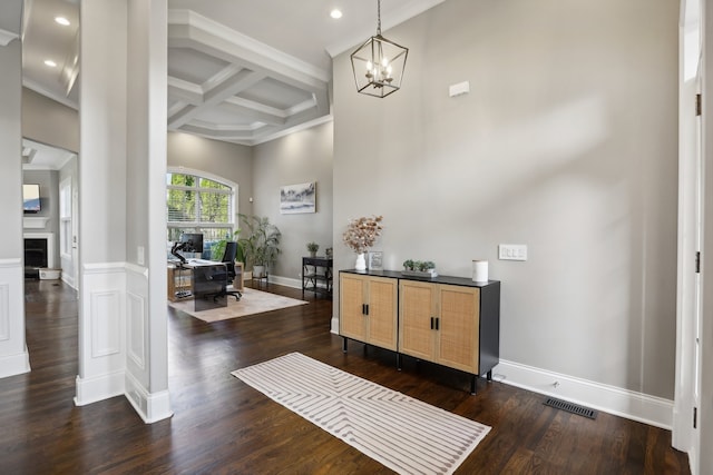 entryway featuring coffered ceiling, crown molding, beam ceiling, a notable chandelier, and dark hardwood / wood-style floors