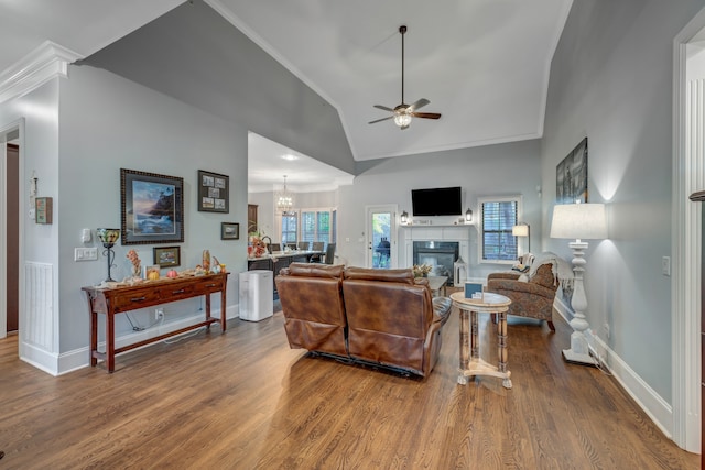 living room featuring wood-type flooring, ceiling fan with notable chandelier, high vaulted ceiling, and crown molding