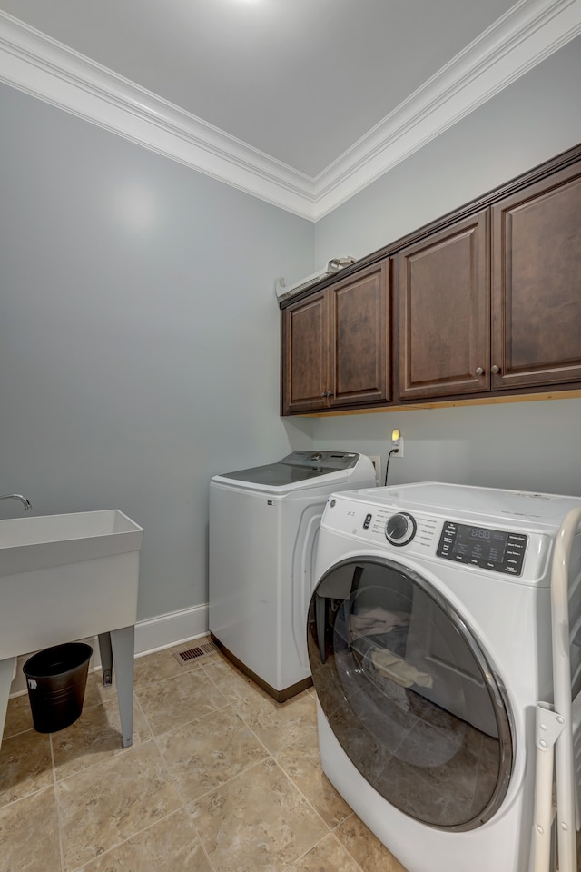 laundry area featuring washer and dryer, cabinets, and ornamental molding