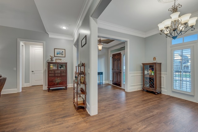 foyer entrance with ornamental molding, dark wood-type flooring, and a notable chandelier