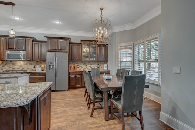 dining space featuring crown molding, a notable chandelier, and light wood-type flooring