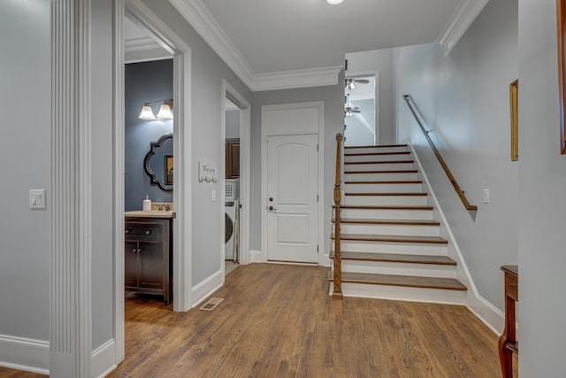 stairs featuring hardwood / wood-style flooring, washer / clothes dryer, and crown molding