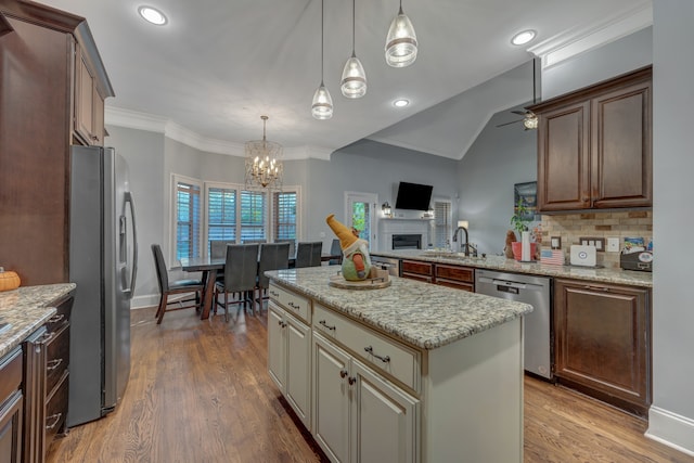 kitchen featuring pendant lighting, a center island, ceiling fan with notable chandelier, wood-type flooring, and stainless steel appliances