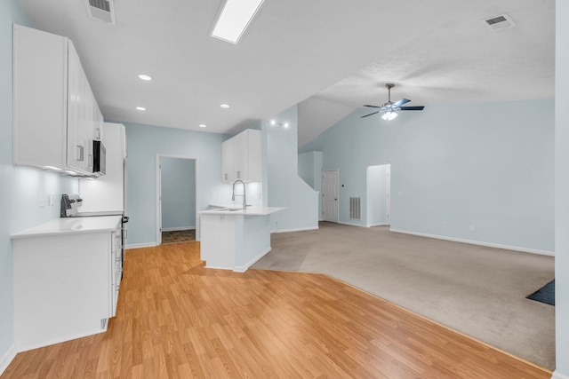 kitchen with sink, vaulted ceiling, ceiling fan, light hardwood / wood-style floors, and white cabinetry