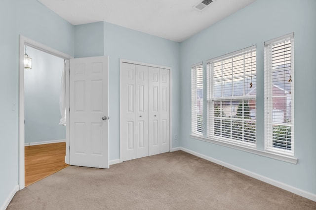 unfurnished bedroom featuring a closet and light colored carpet