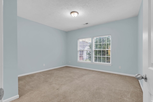 empty room with a textured ceiling and light carpet