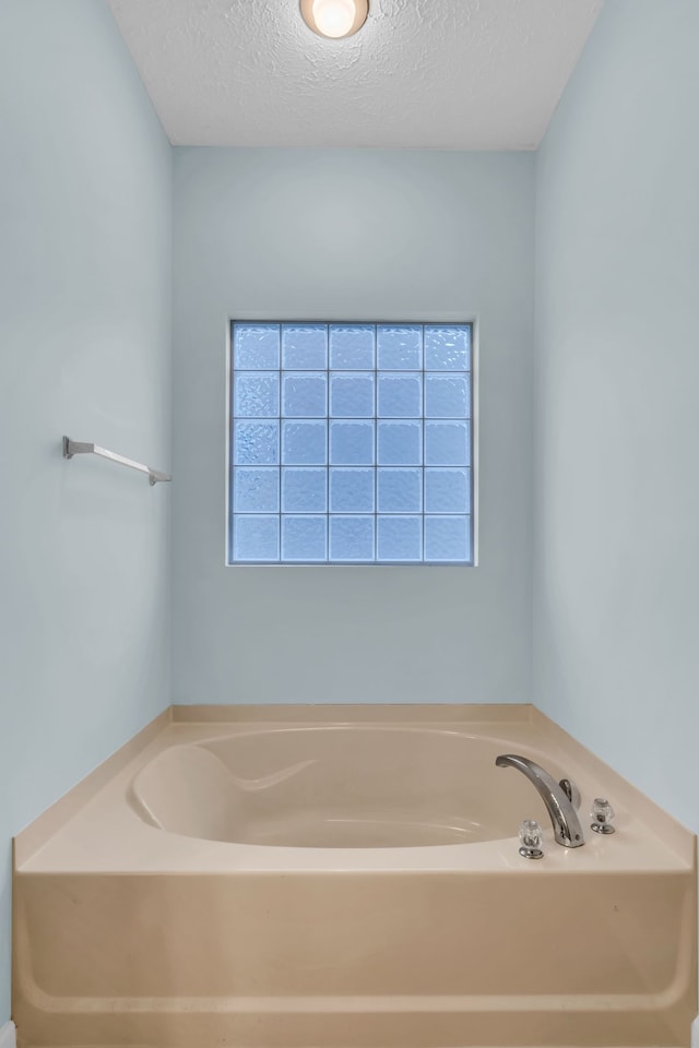 bathroom featuring a tub and a textured ceiling