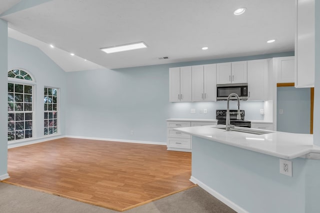 kitchen with white cabinets, stainless steel appliances, lofted ceiling, and light wood-type flooring