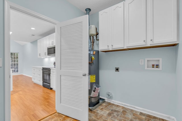 washroom featuring cabinets, washer hookup, hookup for an electric dryer, gas water heater, and light hardwood / wood-style flooring