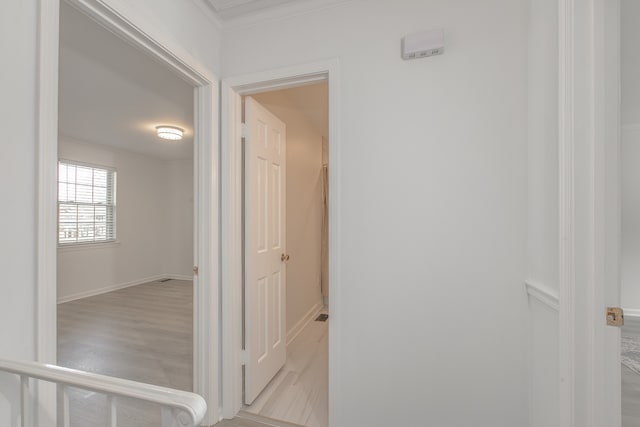 corridor with light hardwood / wood-style flooring and crown molding