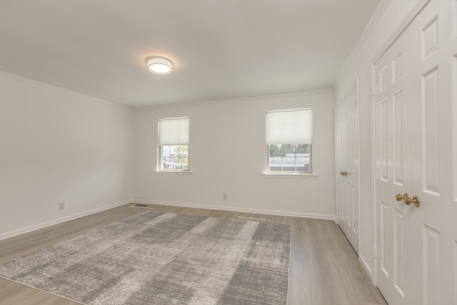 spare room featuring ornamental molding, light hardwood / wood-style floors, and a healthy amount of sunlight