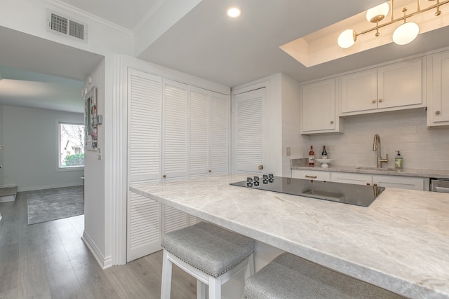 kitchen with white cabinets, a breakfast bar, light wood-type flooring, and ornamental molding