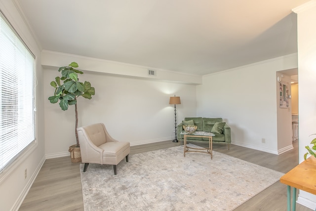 sitting room featuring wood-type flooring, crown molding, and a wealth of natural light