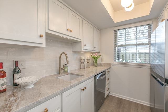 kitchen featuring white cabinetry, sink, light stone countertops, light hardwood / wood-style flooring, and appliances with stainless steel finishes