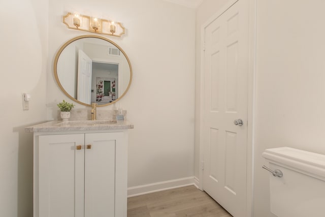 bathroom with hardwood / wood-style floors, vanity, and toilet