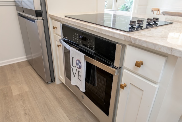 kitchen with light stone counters, stainless steel appliances, and light hardwood / wood-style floors