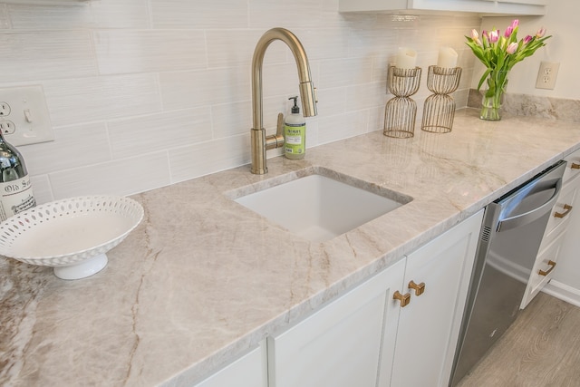 kitchen featuring sink, stainless steel dishwasher, light stone countertops, light hardwood / wood-style floors, and white cabinetry