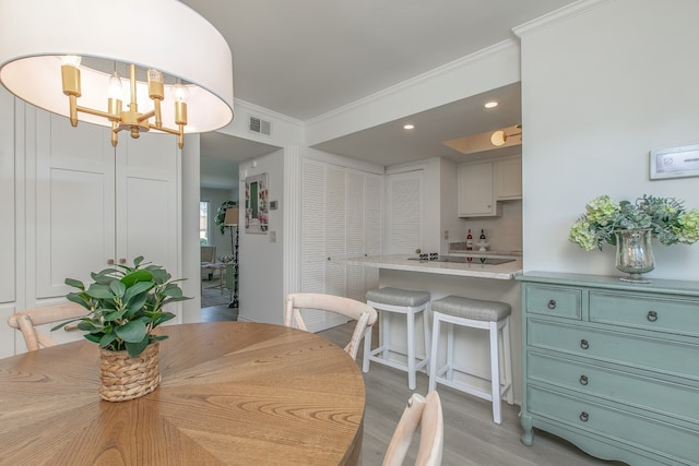 dining room with light hardwood / wood-style floors, crown molding, and an inviting chandelier