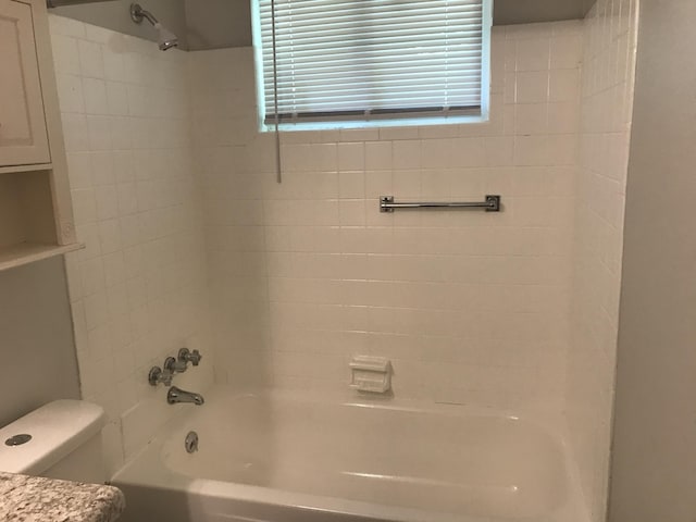 bathroom featuring toilet and tiled shower / bath