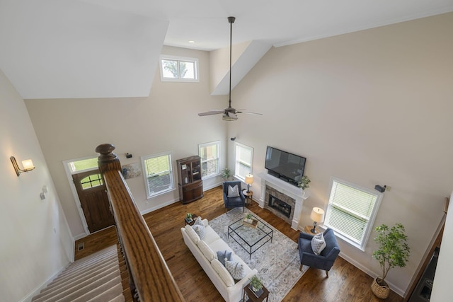 living room featuring ceiling fan, a towering ceiling, and hardwood / wood-style flooring