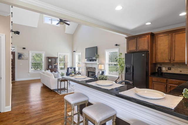 kitchen featuring black fridge with ice dispenser, dark hardwood / wood-style floors, ceiling fan, and a healthy amount of sunlight