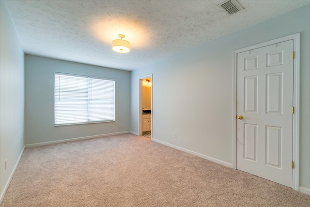 unfurnished room with light colored carpet and a textured ceiling