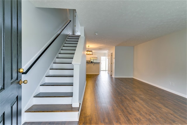 stairway featuring wood-type flooring and a textured ceiling