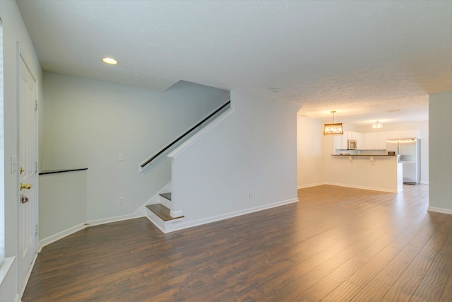 unfurnished living room featuring a textured ceiling and dark hardwood / wood-style floors