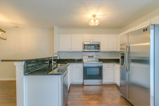 kitchen with white cabinetry, sink, dark hardwood / wood-style flooring, kitchen peninsula, and appliances with stainless steel finishes