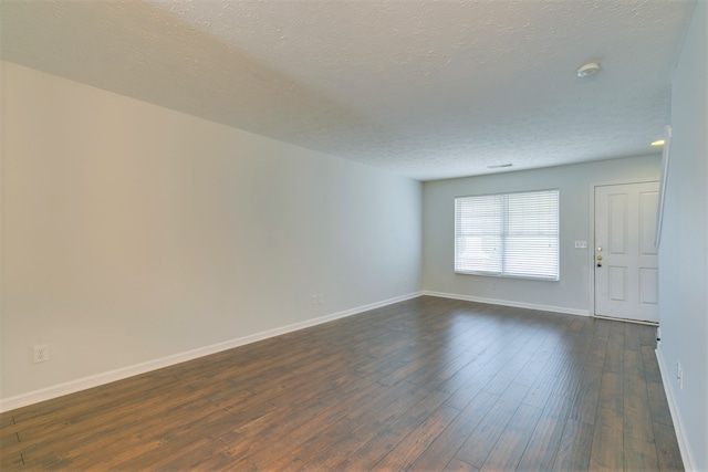 empty room featuring dark hardwood / wood-style floors and a textured ceiling