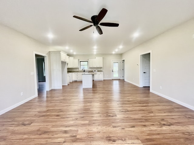 unfurnished living room with light hardwood / wood-style floors, ceiling fan, and sink