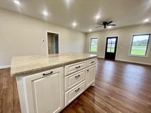 kitchen with white cabinetry, light stone countertops, ceiling fan, dark hardwood / wood-style flooring, and a kitchen island