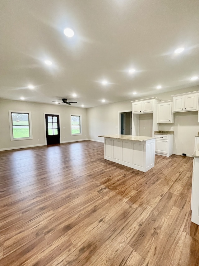 kitchen with a healthy amount of sunlight, a kitchen island, white cabinetry, and light hardwood / wood-style flooring