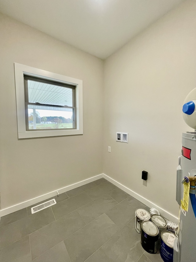 laundry area with water heater, washer hookup, and dark tile patterned flooring