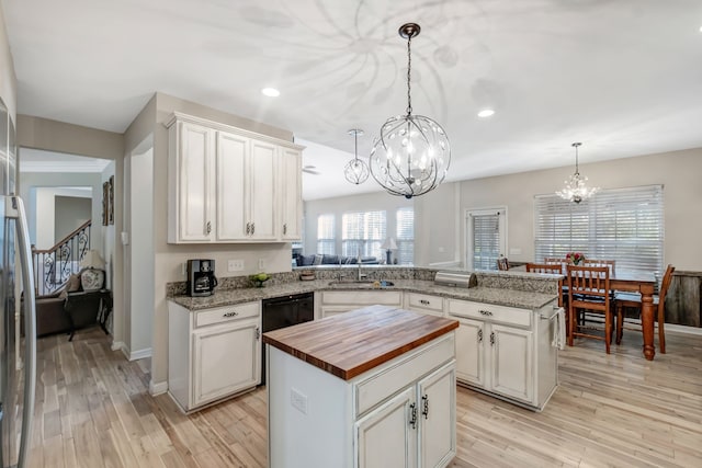 kitchen with kitchen peninsula, light hardwood / wood-style flooring, a kitchen island, and hanging light fixtures