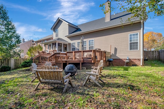 rear view of property featuring a yard, a deck, and an outdoor fire pit