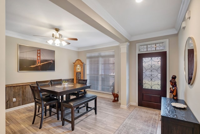 dining room with light wood-type flooring, ornamental molding, and wooden walls