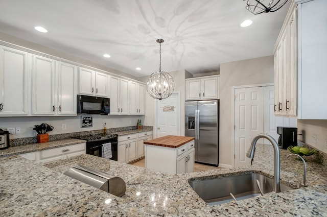 kitchen with black appliances, white cabinets, sink, butcher block countertops, and a kitchen island